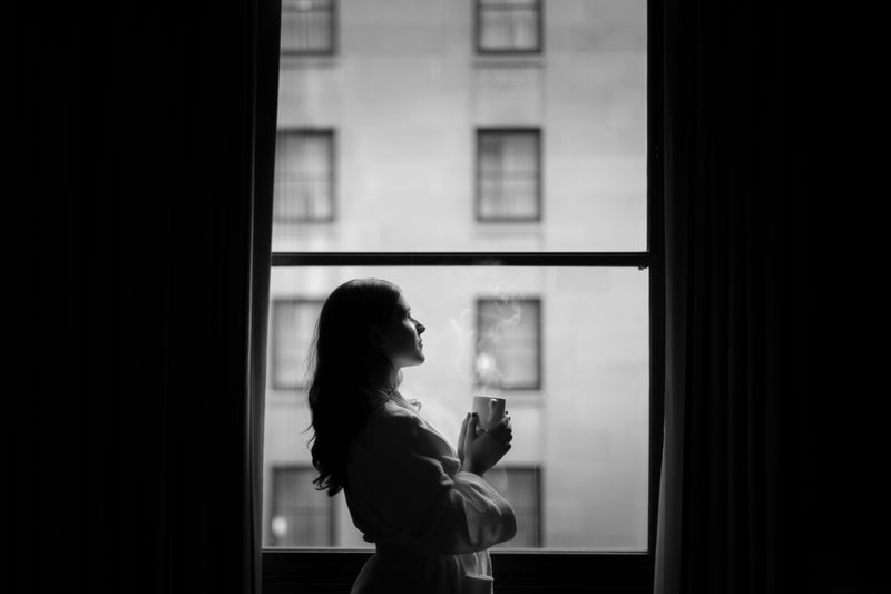 woman in hotel room window with coffee